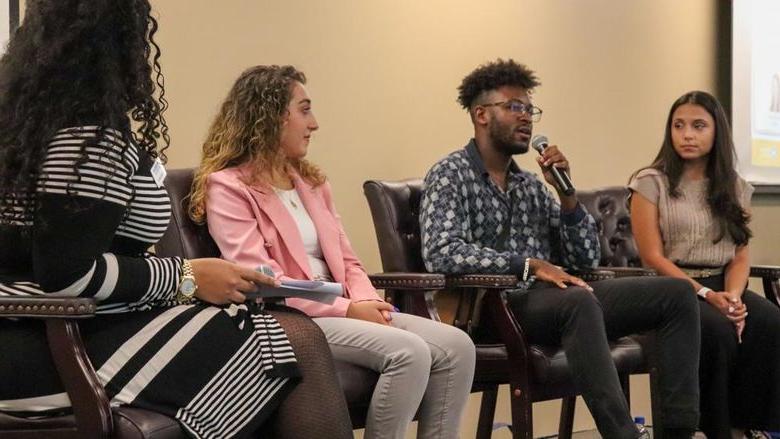 Three students on stage in panel setting