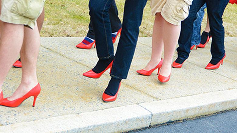 Men wearing red high heels walking around campus