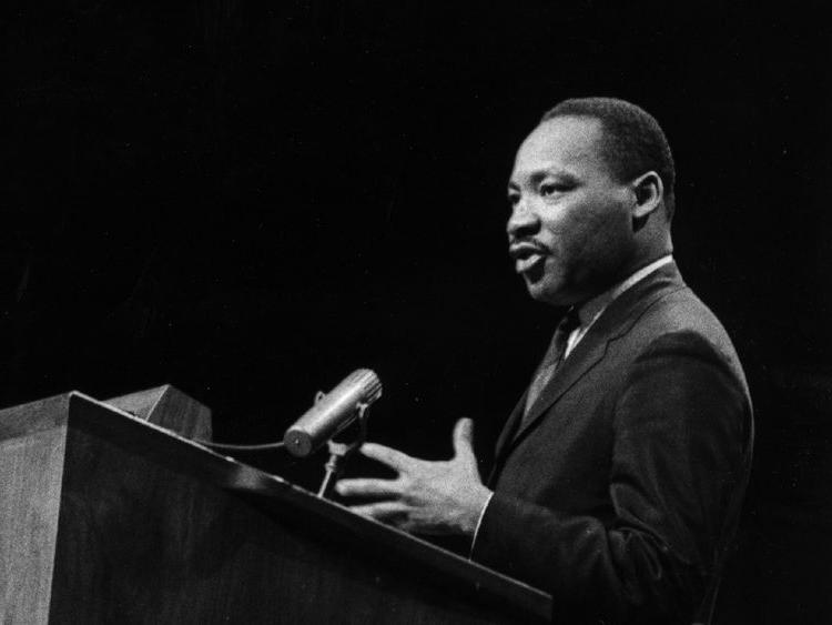 A black and white image of Martin Luther King speaking at a podium